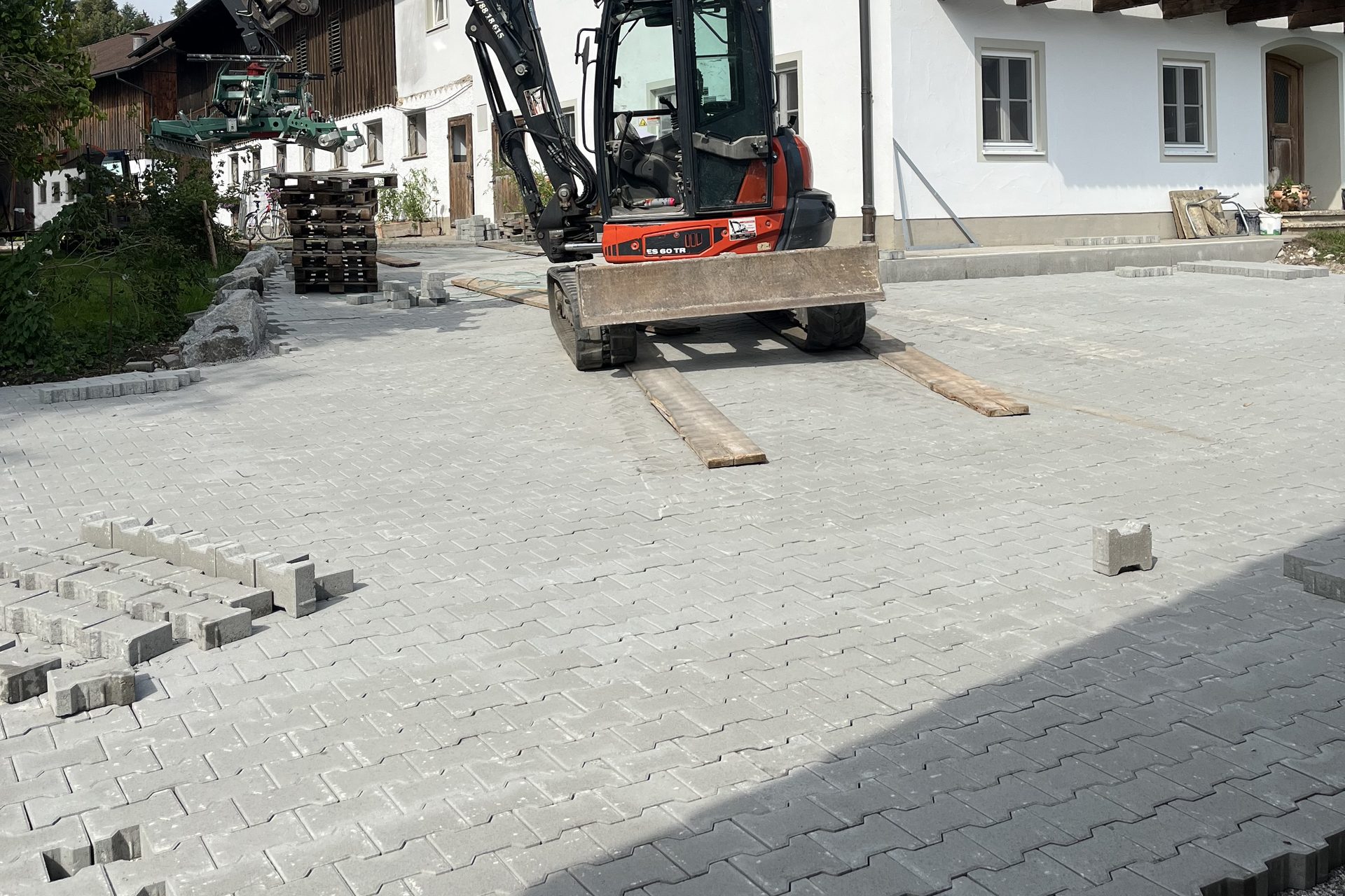 Bagger beim Pflastern einer großen Hoffläche